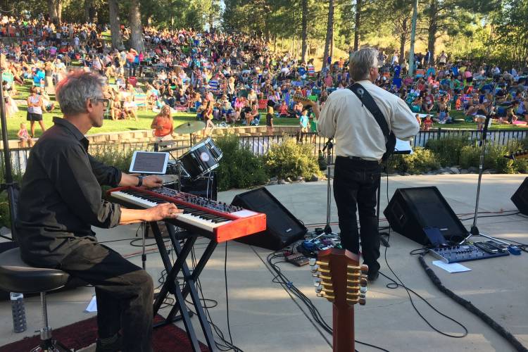 Band playing on stage for a crowed of people in a park