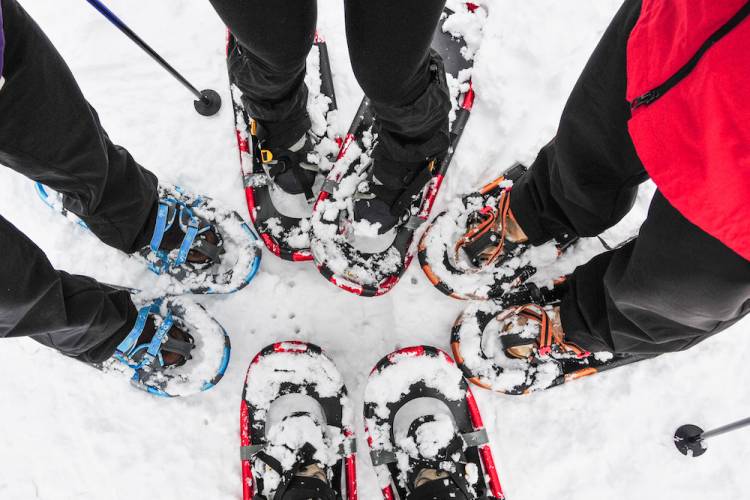 view of family's feet all wearing snowshoes