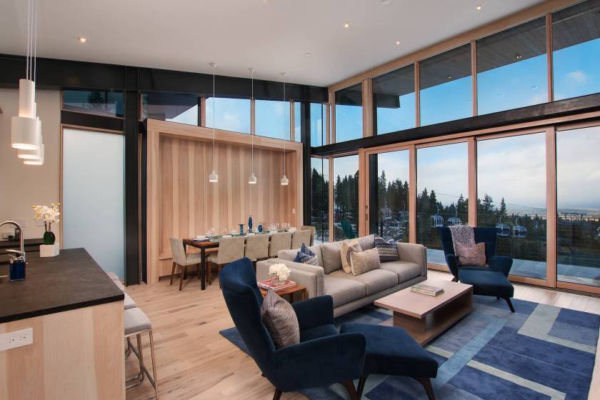 A vacation rental interior with floor-to-ceiling windows and ski terrain in the background