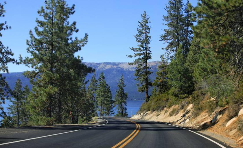 open road along a cliffside with views of lake tahoe in california on a bright sunny day
